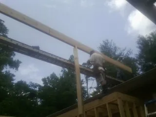 Carpenter setting a ridge beam over a new addition frame — Ice Dam Removal by Roofing Brothers in Sonyea