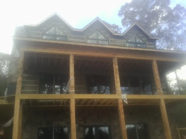 Dormers and porch framing on a large log home under construction — Roof Coating work by our crew in Sonyea