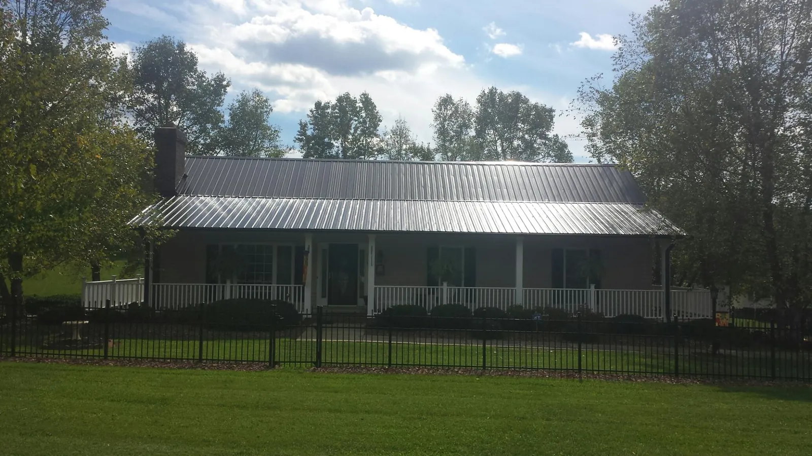 Gray metal roof on a brick ranch with a full width front porch — Gutter Guard Installation work by our crew in Sonyea