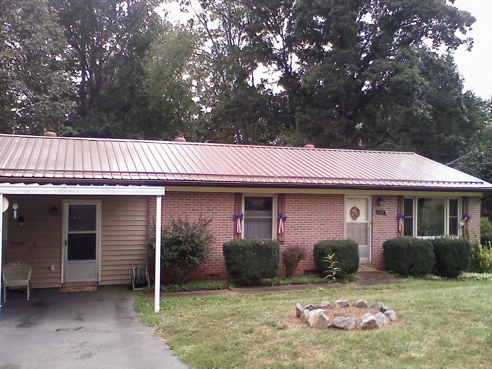 Bronze metal roof and carport on a brick ranch home — Roof Repair work by our crew in Sonyea