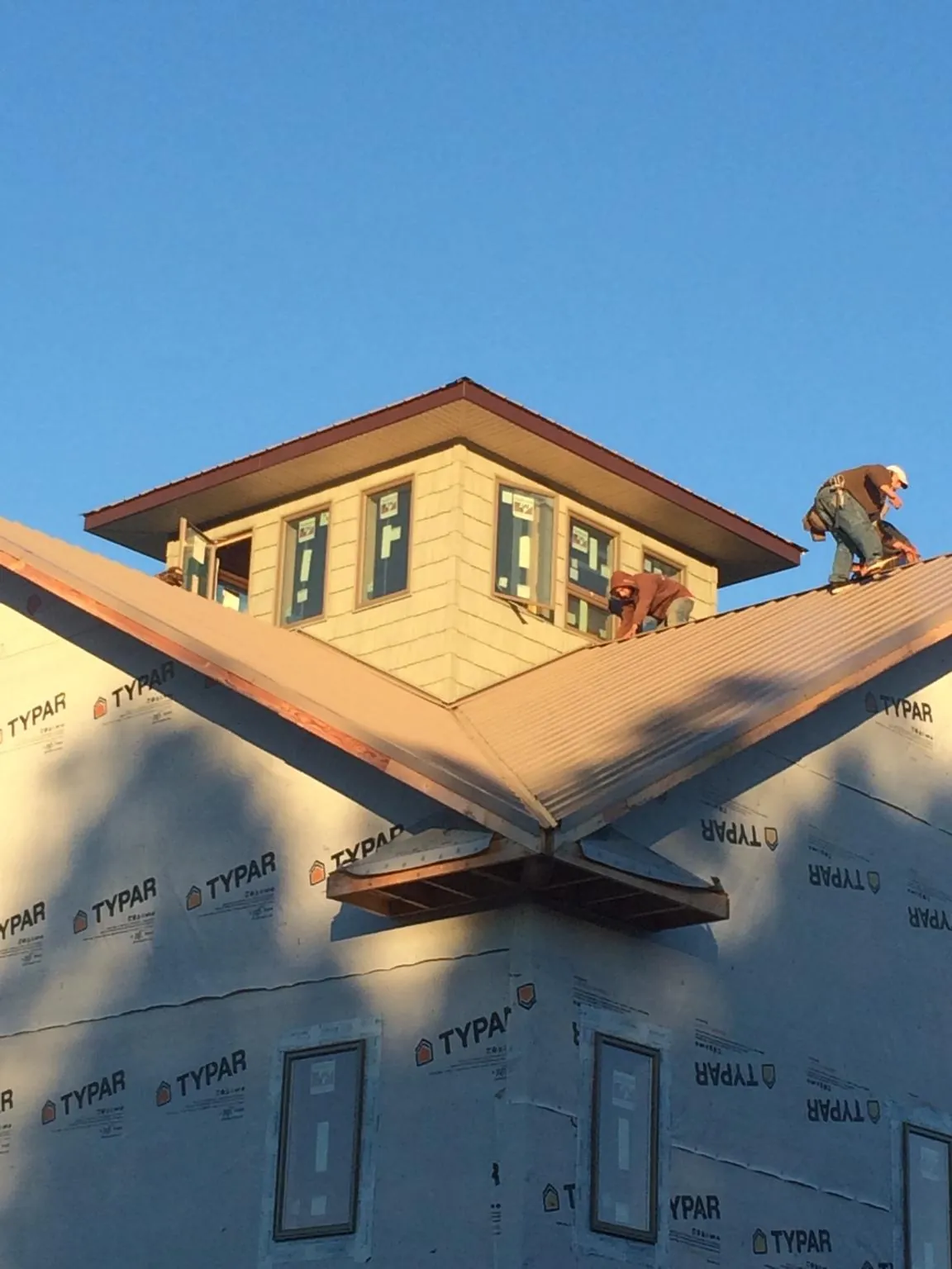Roofers working around a rooftop cupola on a new metal roof at sunset — Roof Waterproofing in Sonyea by Roofing Brothers